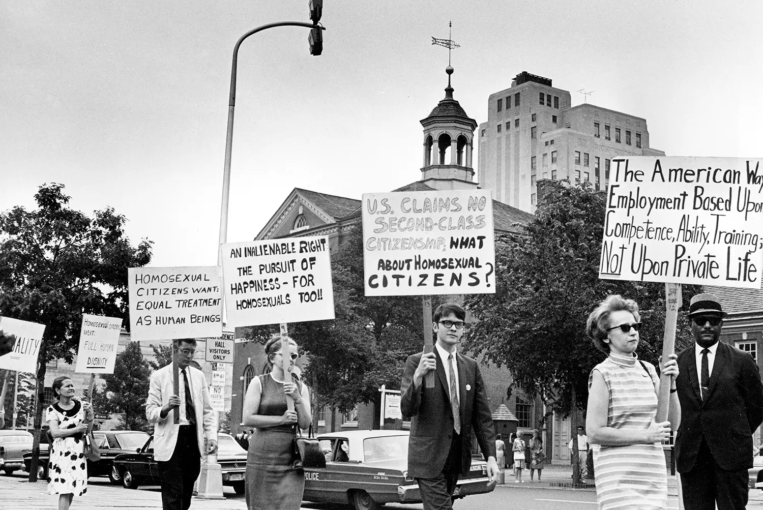 A group of protesters march with signs containing statements such as “U.S. claims no second-class citizenship. What about homosexual citizens?” and “The American Way: Employment based upon competence, ability, training; not upon private life” and “an inalienable right the pursuit of happiness - for homosexuals too!!” and “homosexual citizens want equal treatment as human beings.”